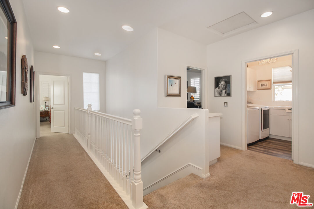 Upstairs hallway with carpet, framed pictures, and a white railing around the stair opening.