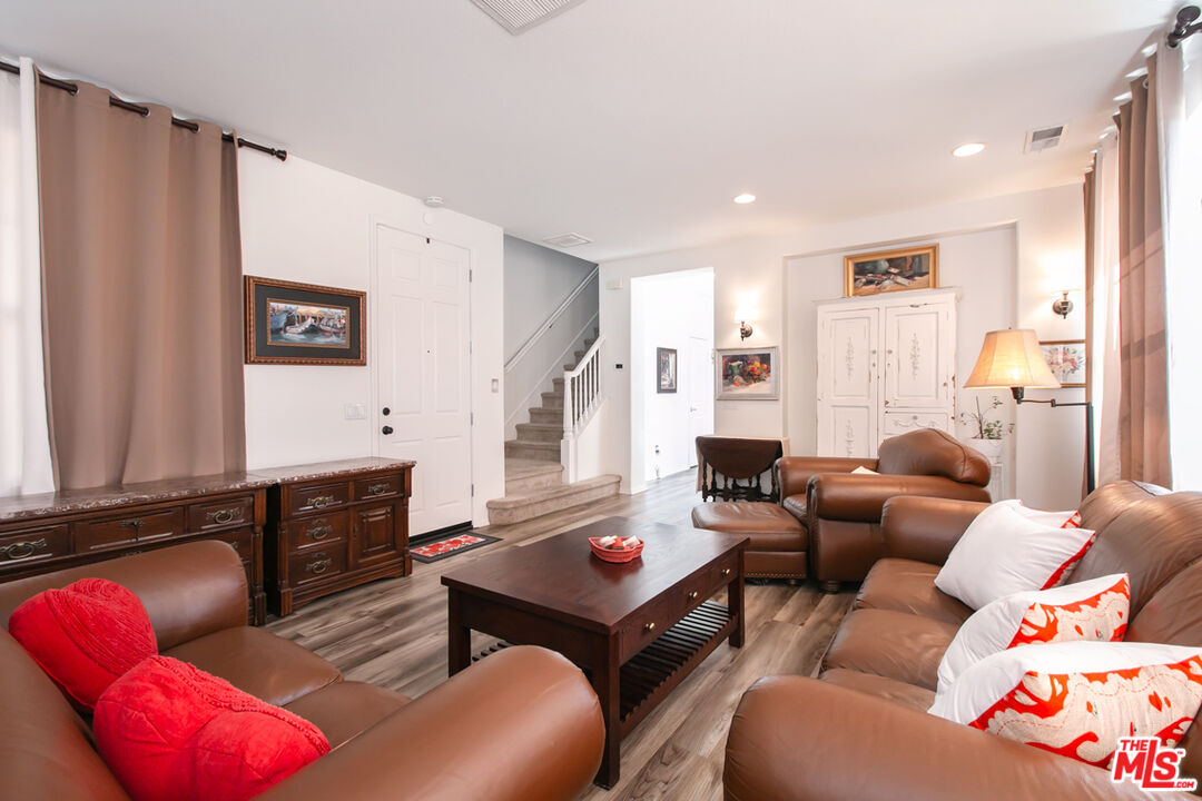 Furnished living room with brown leather seating, a dark wood coffee table, and a staircase.