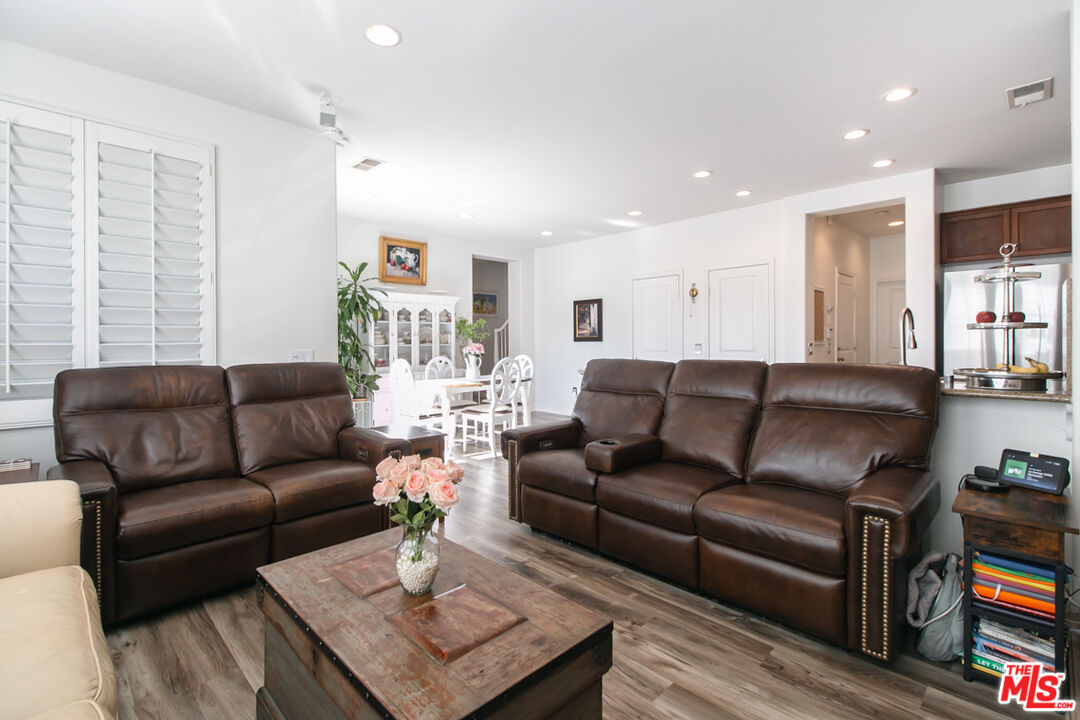 Living room with brown leather sofas, a rustic coffee table, and a dining area behind the seating.
