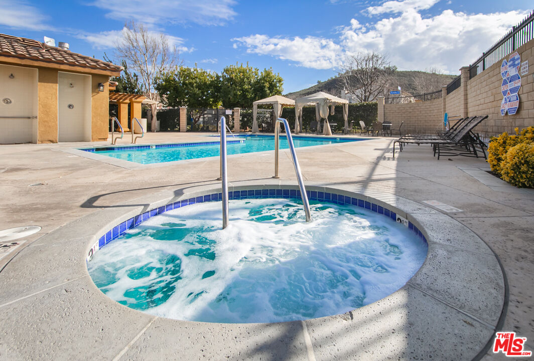 Outdoor spa and swimming pool with cabanas and lounge chairs.