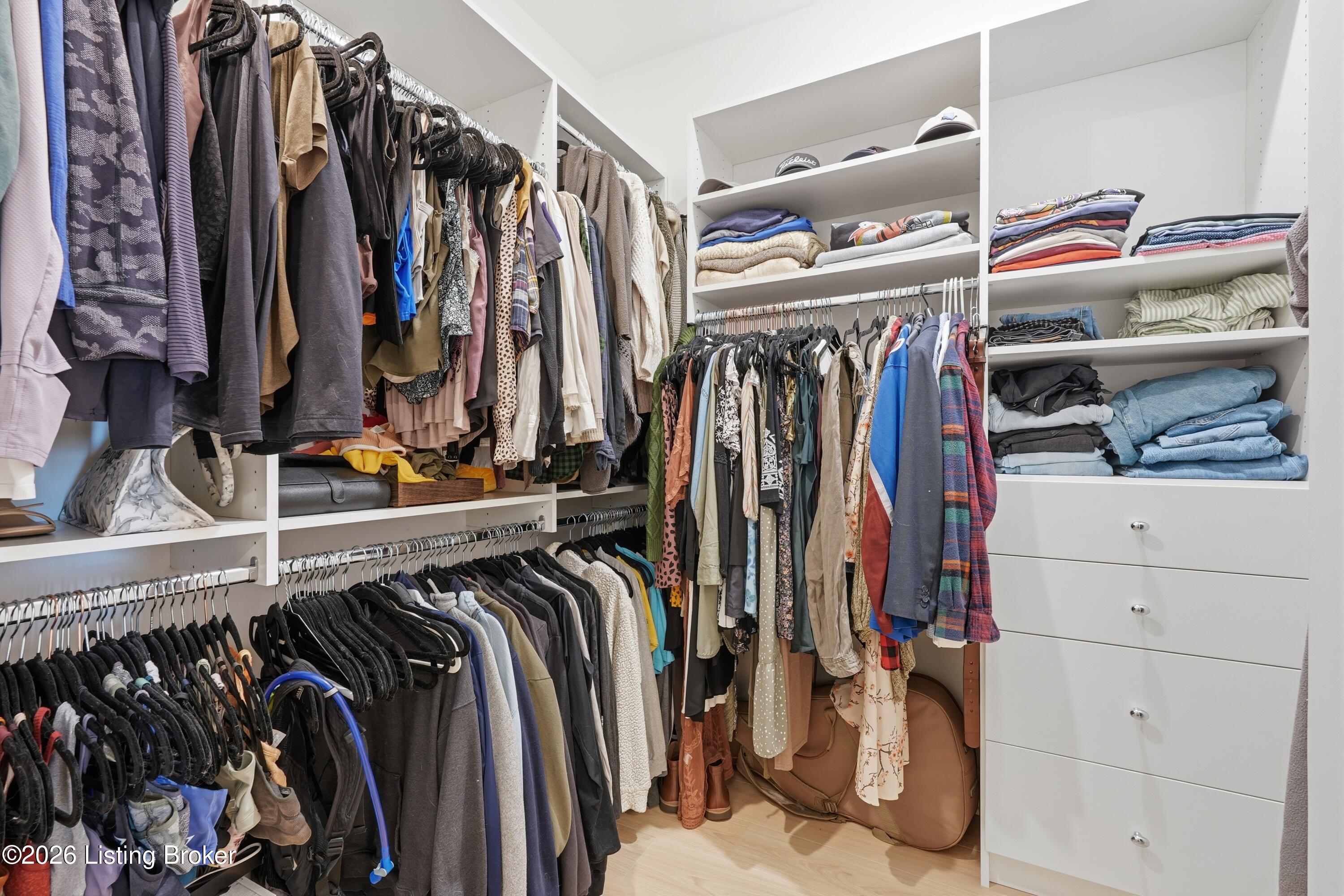 Walk-in closet with extensive clothing racks, folded garments, and built-in drawers.