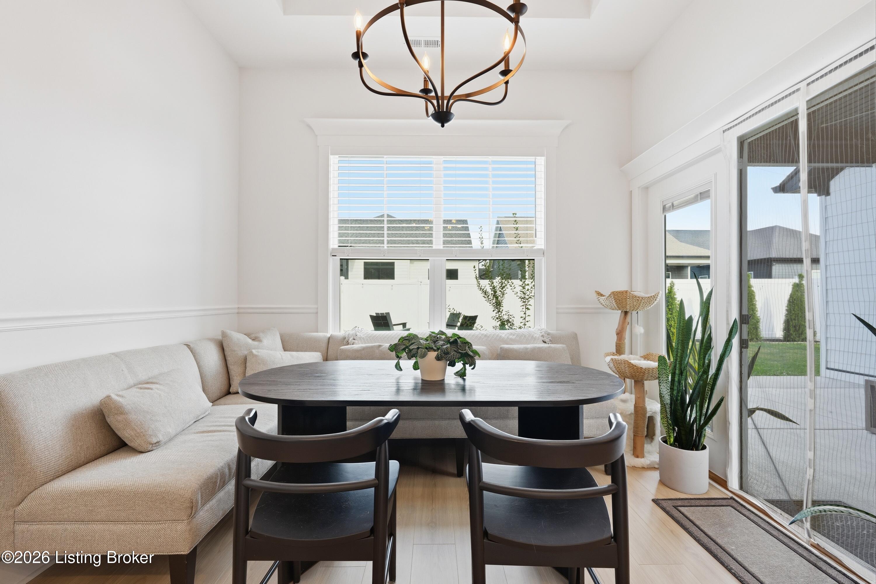 Dining area with a dark table, upholstered banquette, chandelier, and sliding glass doors to the patio.