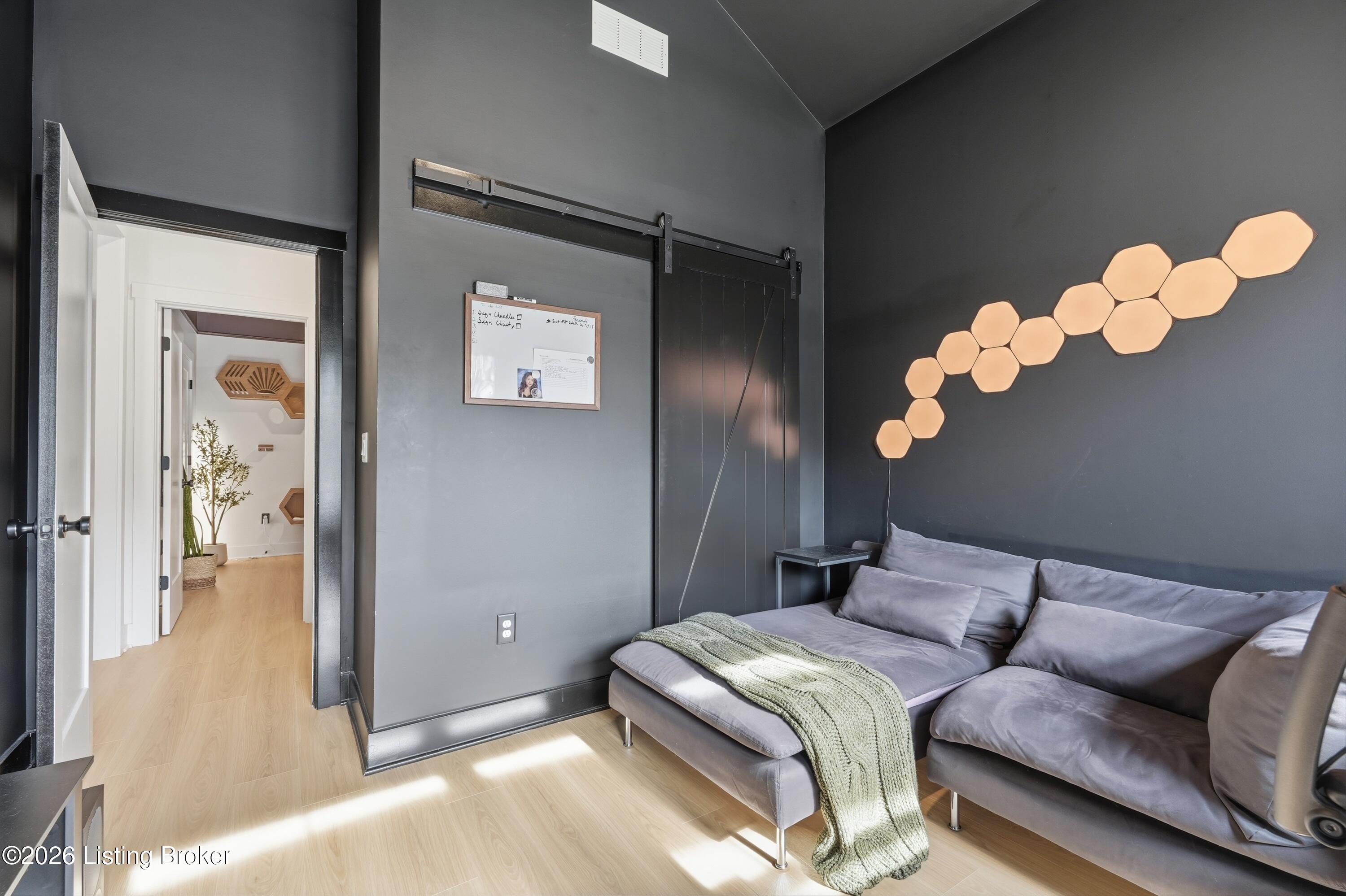 Living room with a gray sectional, hexagonal wall lights, and a sliding barn door.
