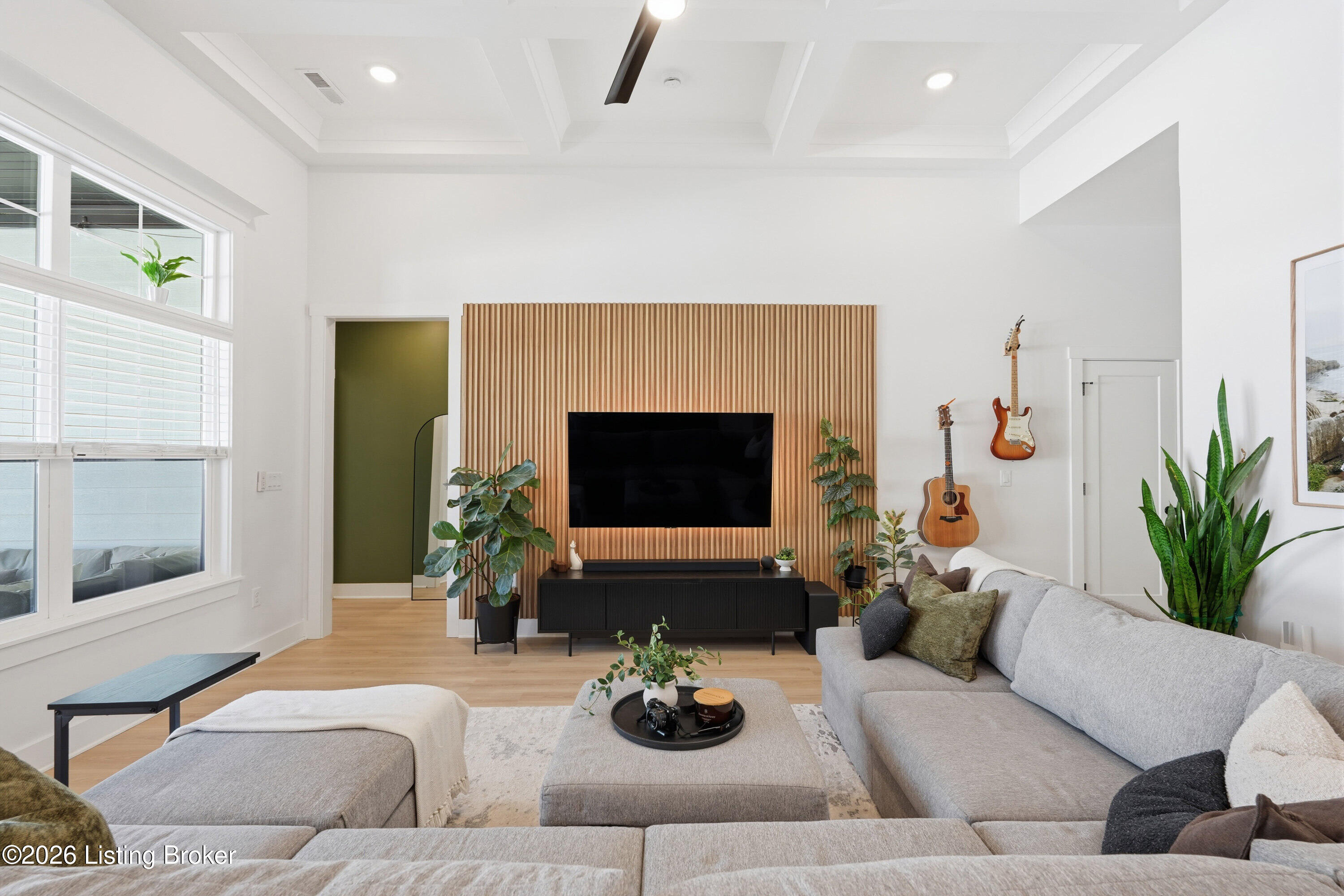 Living room with a wood-slat television wall, tall windows, and a gray sectional sofa.