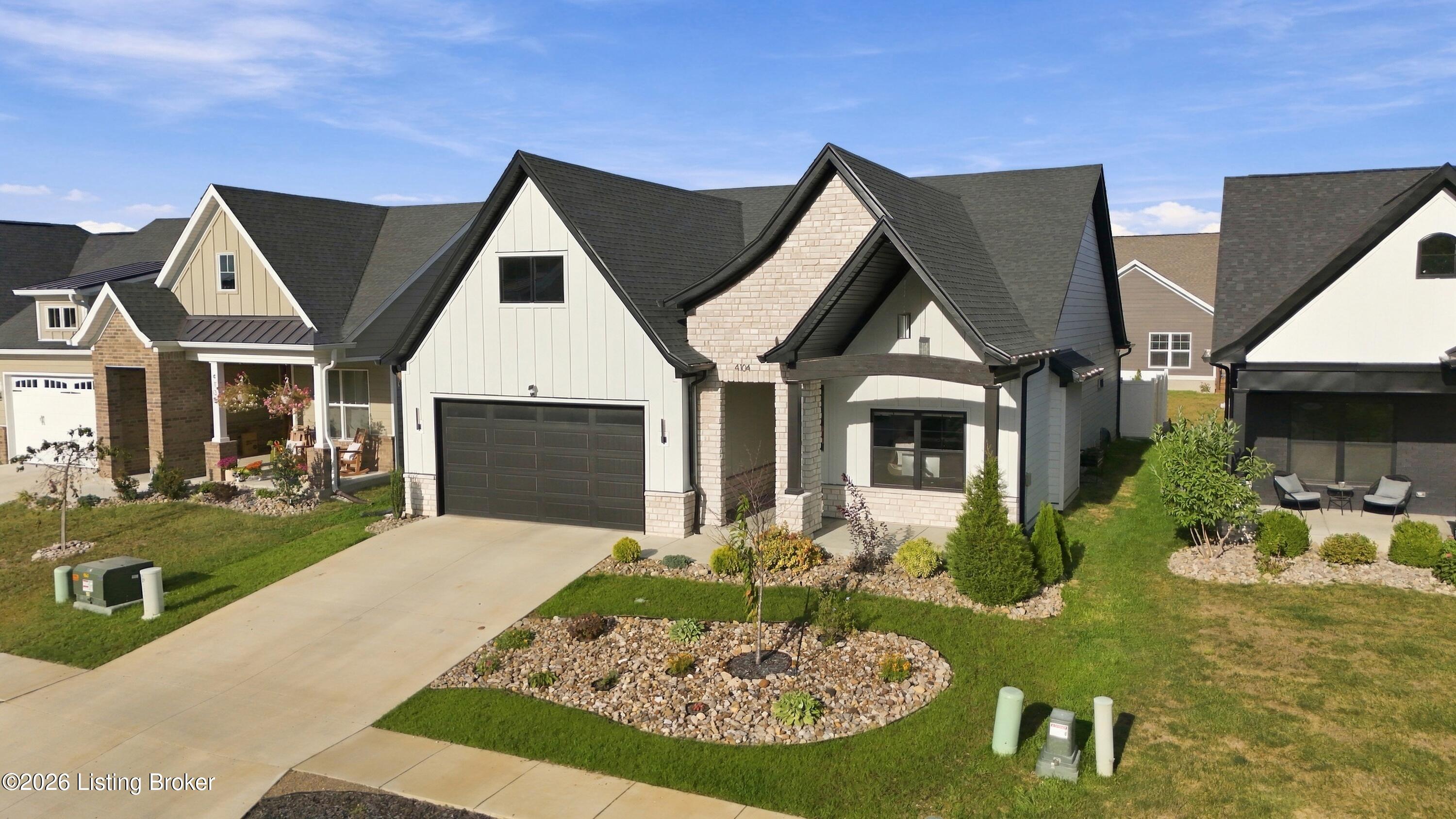 Modern light-brick home with steep gables, dark garage door, and landscaped front yard.