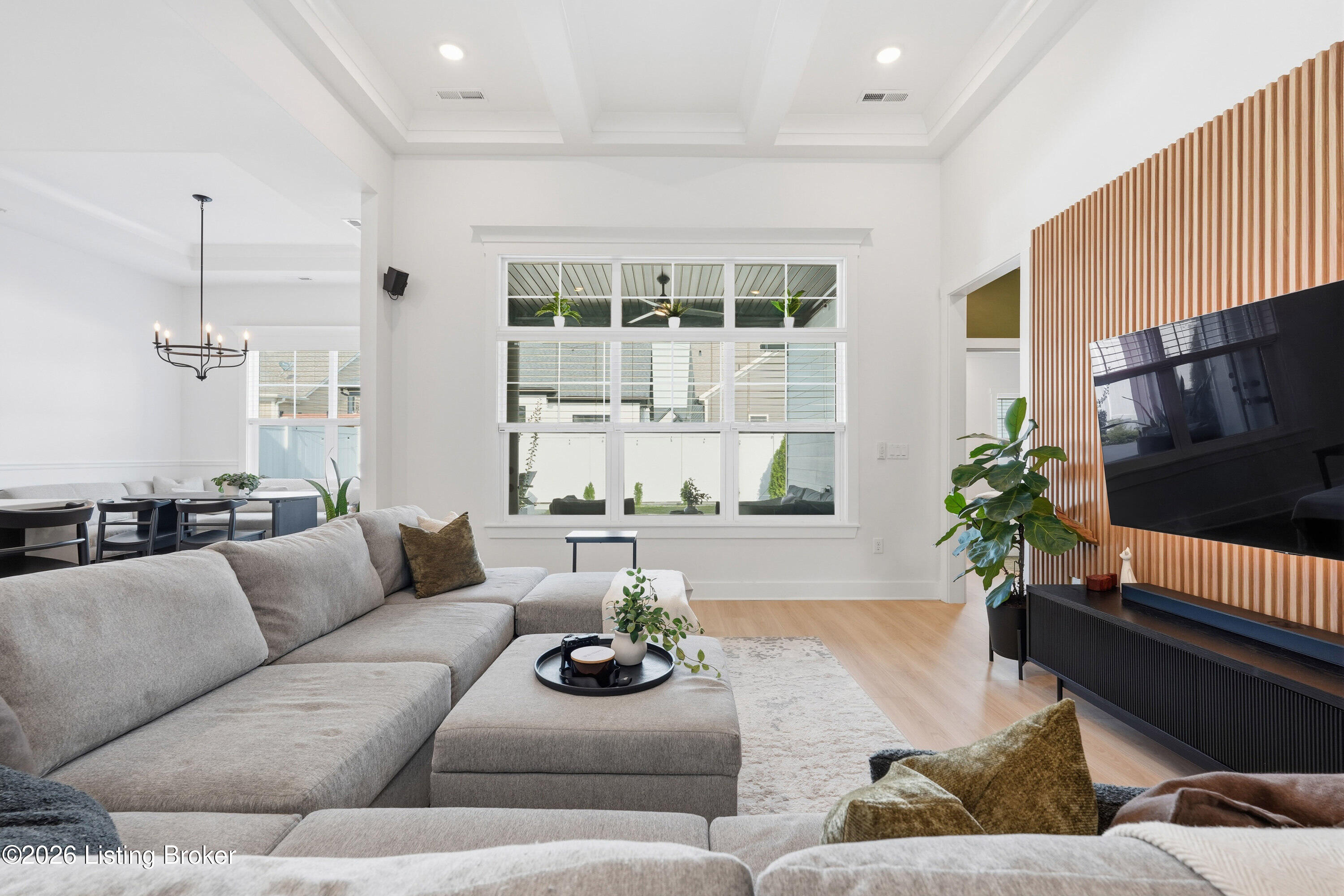 Living room with a gray sectional, large windows, and a wood-slat media wall.