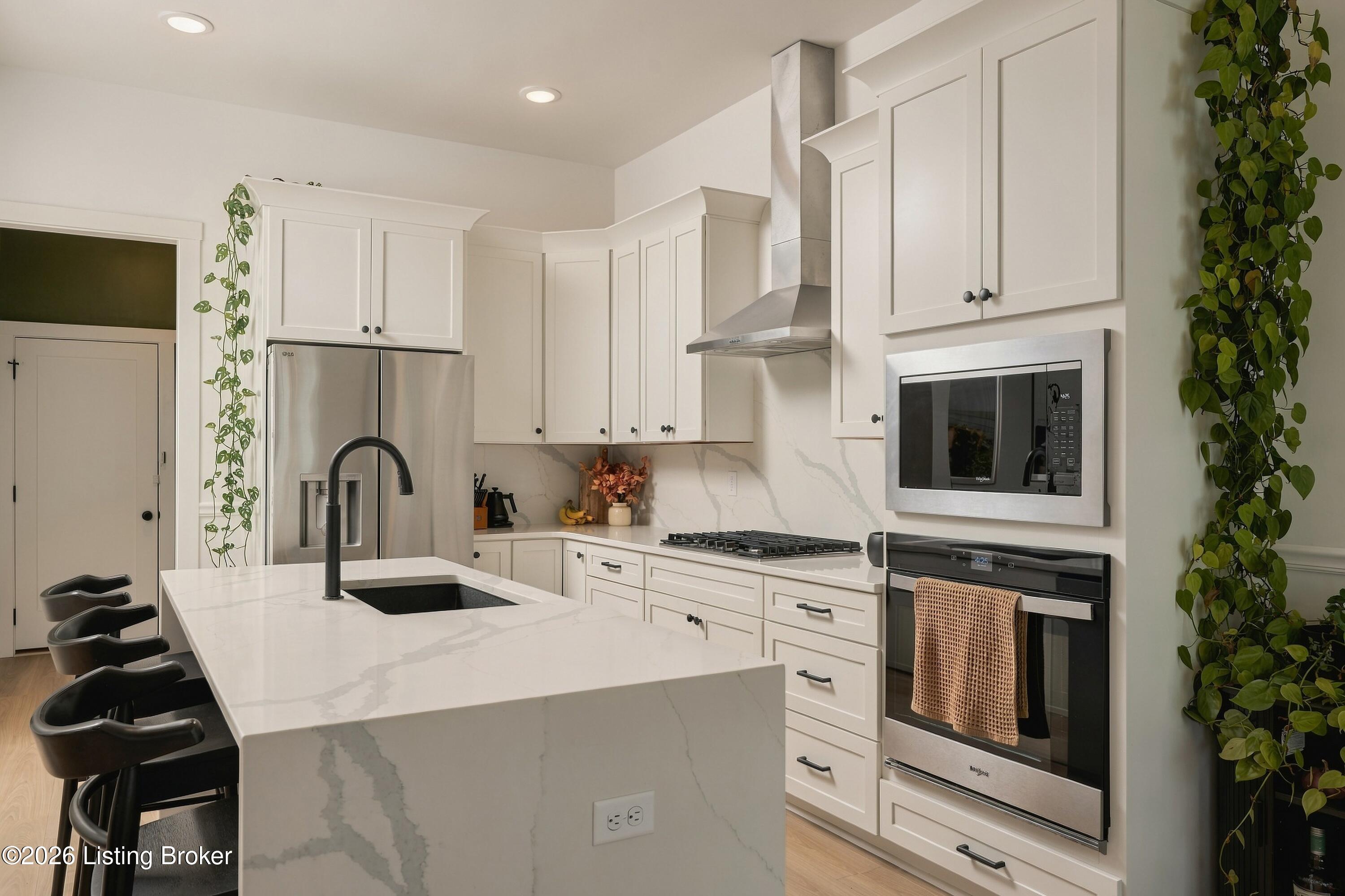Bright remodeled kitchen with a veined stone island, white cabinetry, and stainless steel appliances.