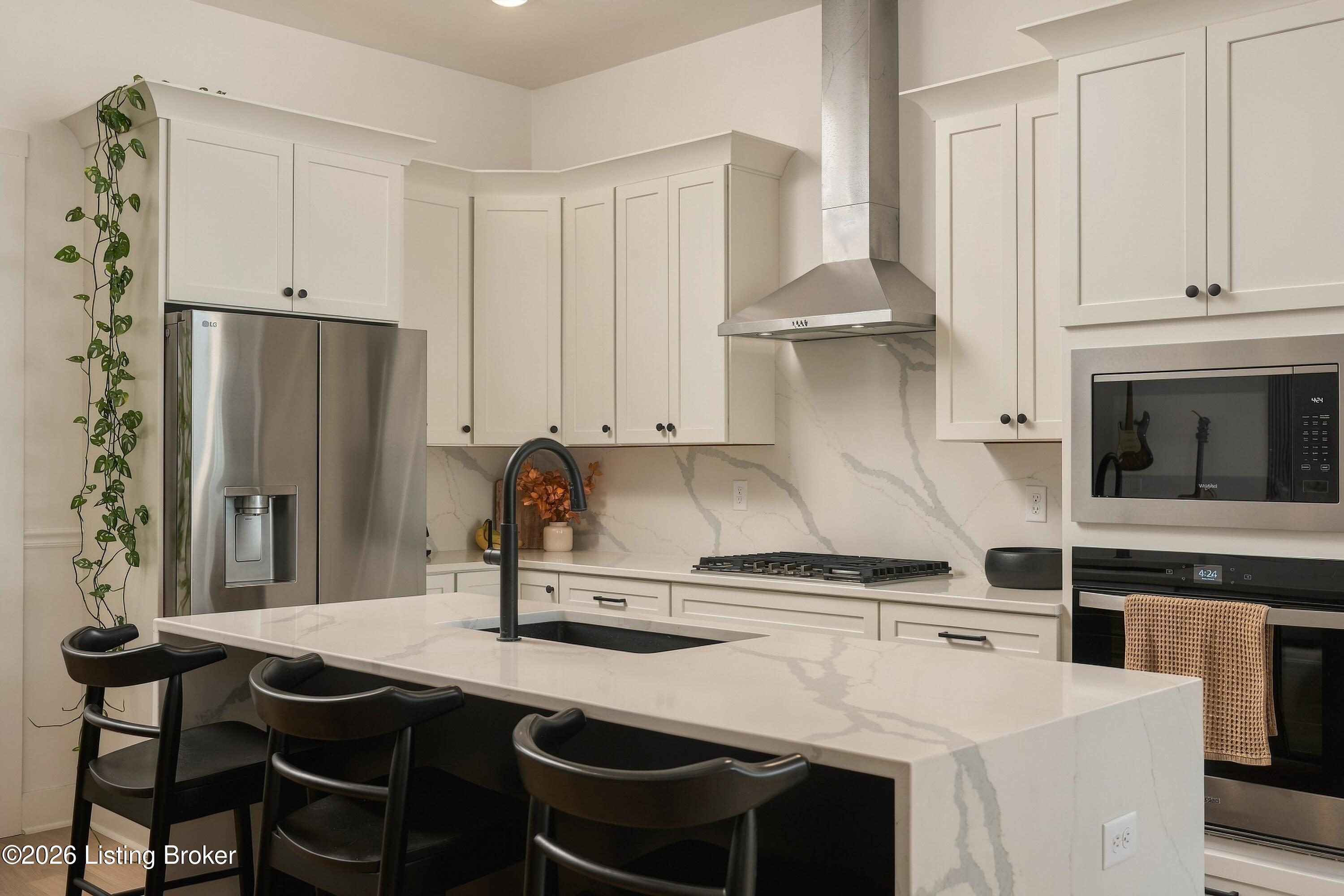 Kitchen with a large veined-stone island, white cabinets, stainless appliances, and a gas cooktop.