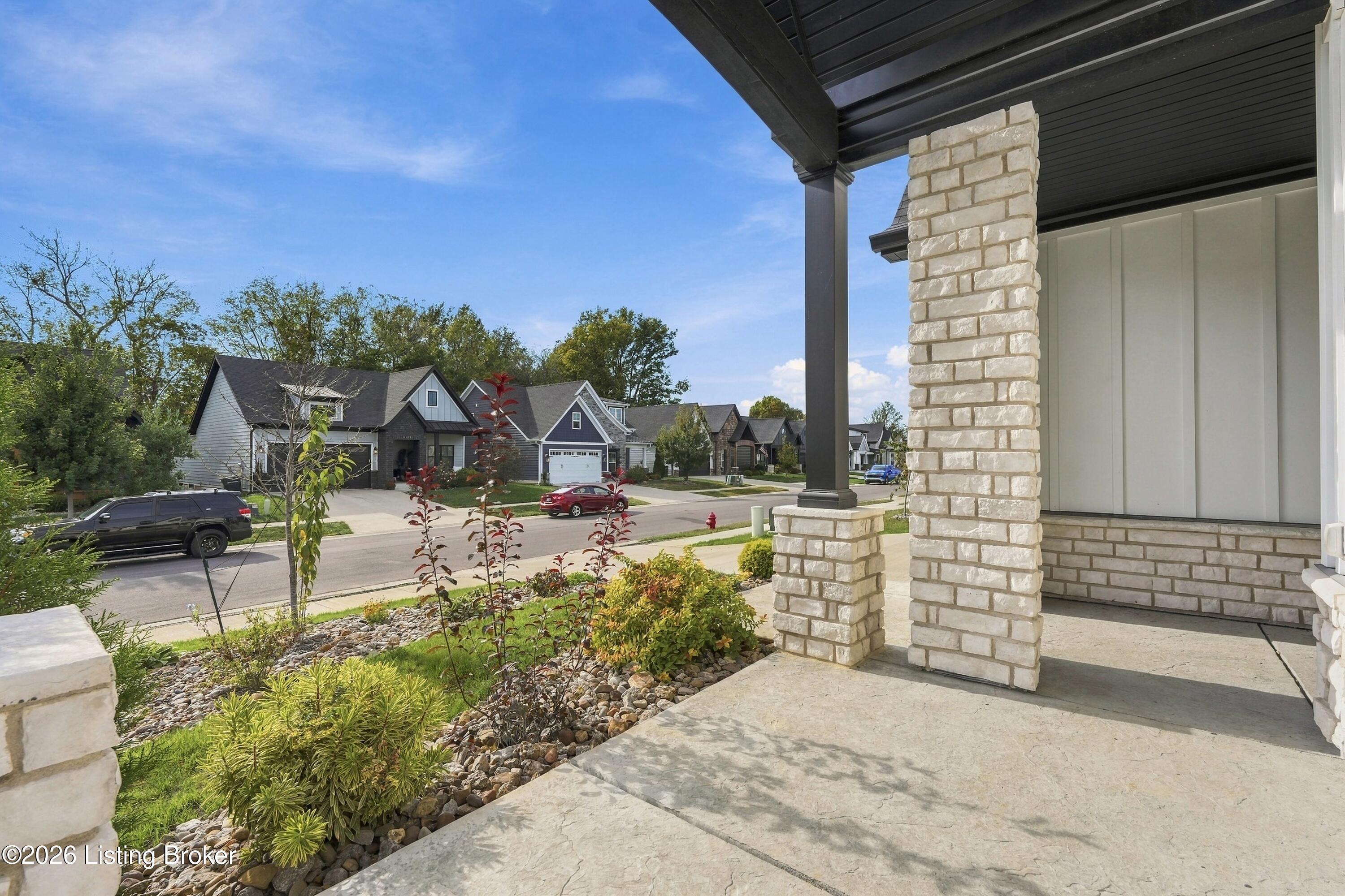 Covered stone porch overlooking a landscaped street of neighboring homes.