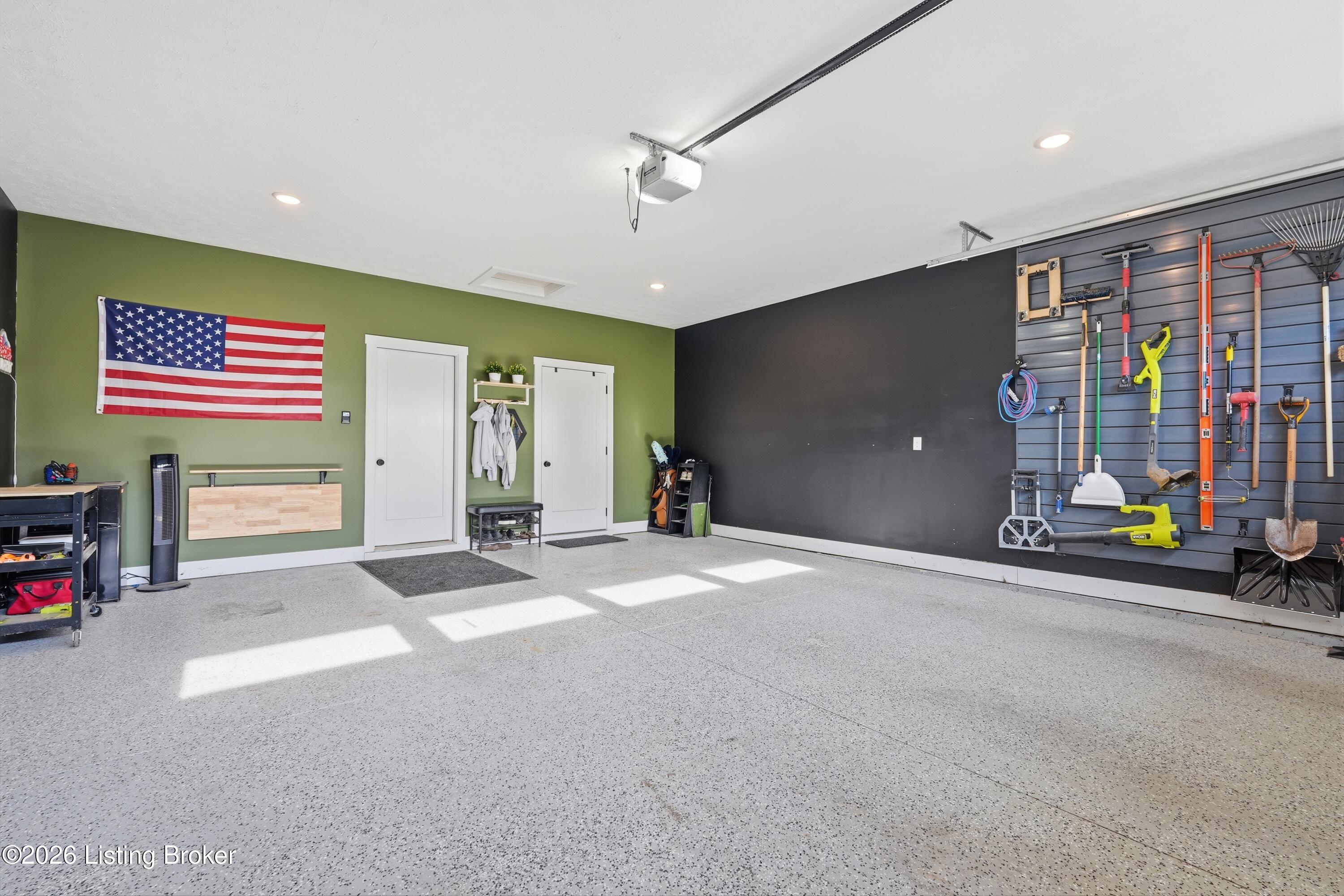 Garage with speckled flooring, a wall-mounted tool organizer, and an American flag.