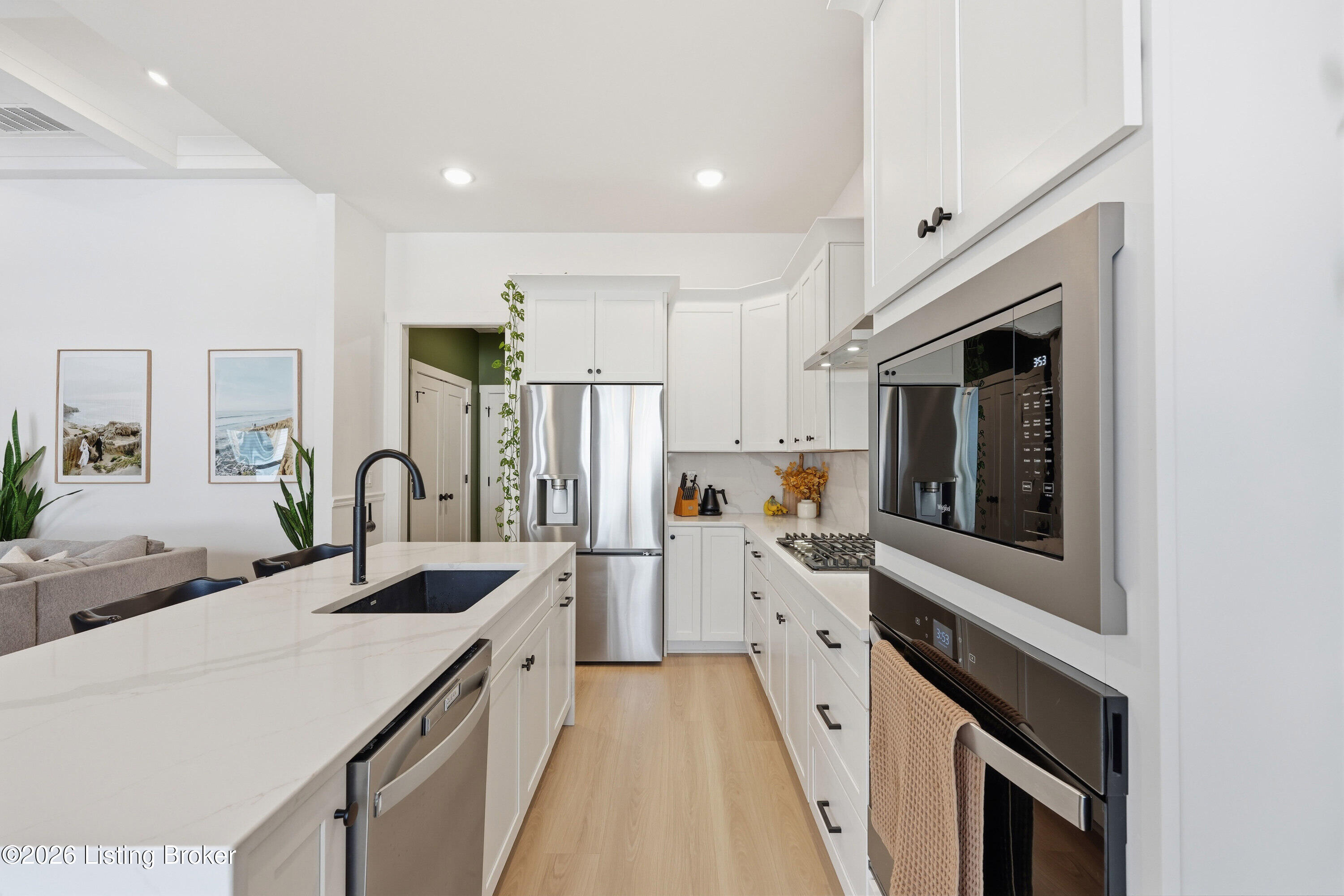 Bright white kitchen with a large island, stainless steel appliances, and gas cooktop.