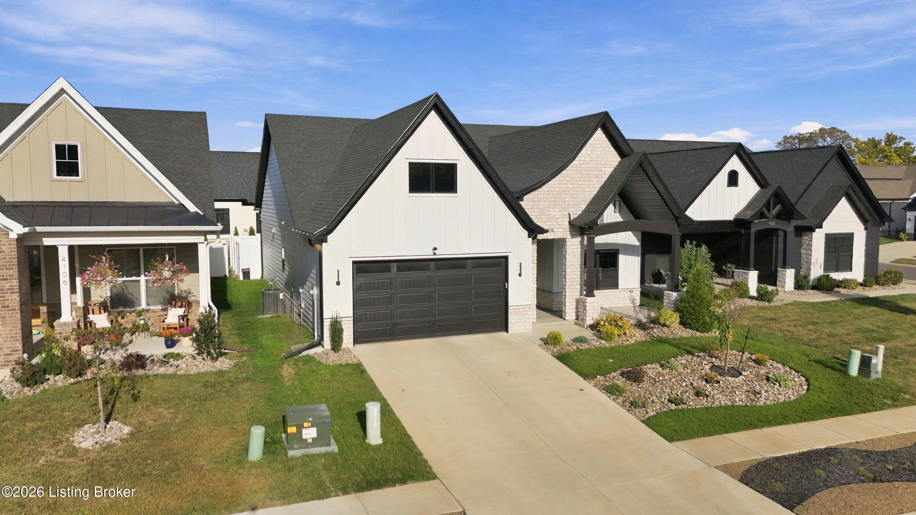 White gabled home with dark double garage, driveway, and landscaped front yard.
