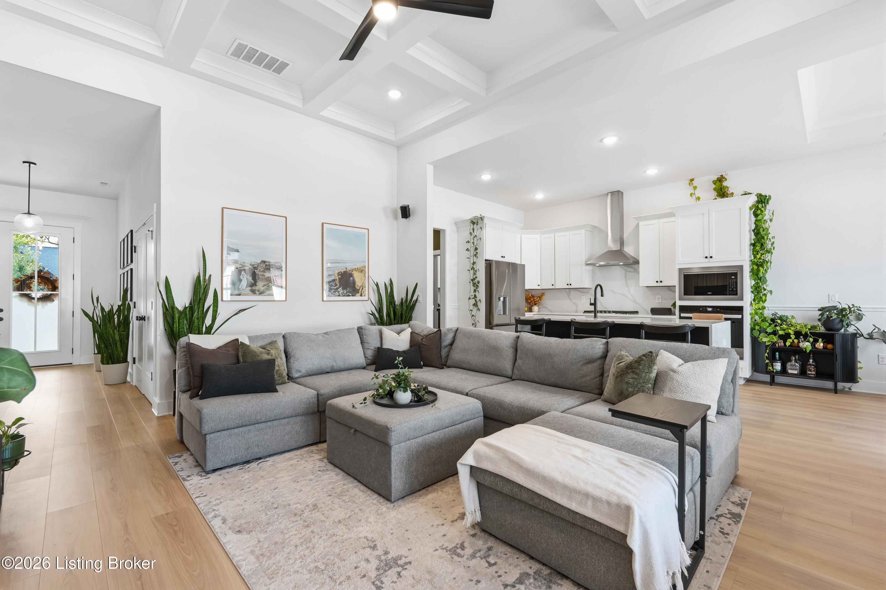 Open-plan living room and kitchen with a gray sectional and white cabinetry.