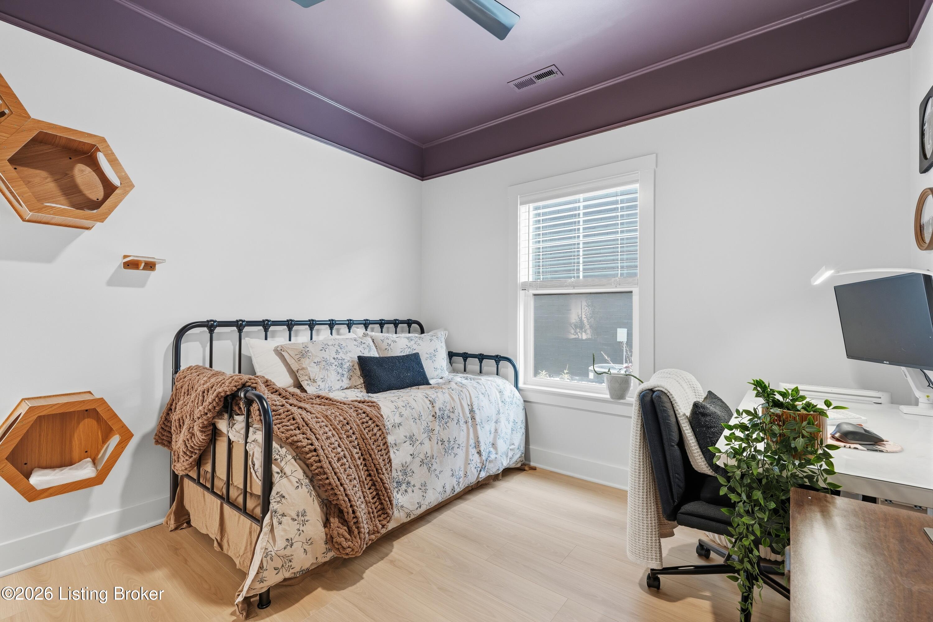 Bedroom with a black metal bed, cat shelves, and a desk beside the window.