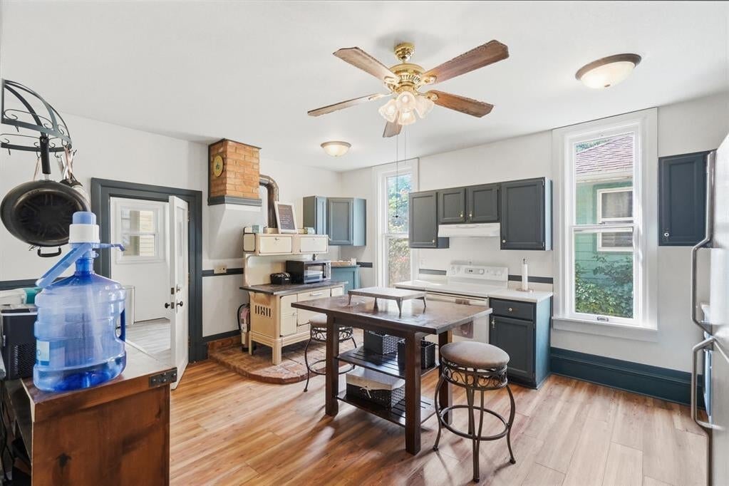Kitchen with charcoal cabinets, a brick stove, hardwood floors, and a central dining table.