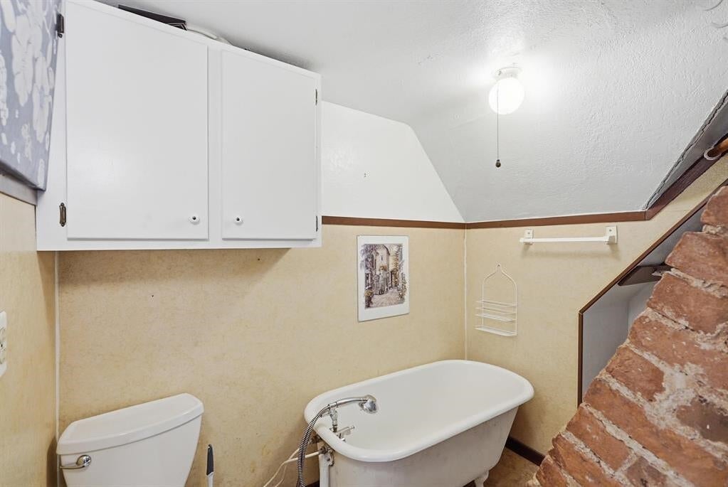 Bathroom with a freestanding tub beside a stone-faced staircase.