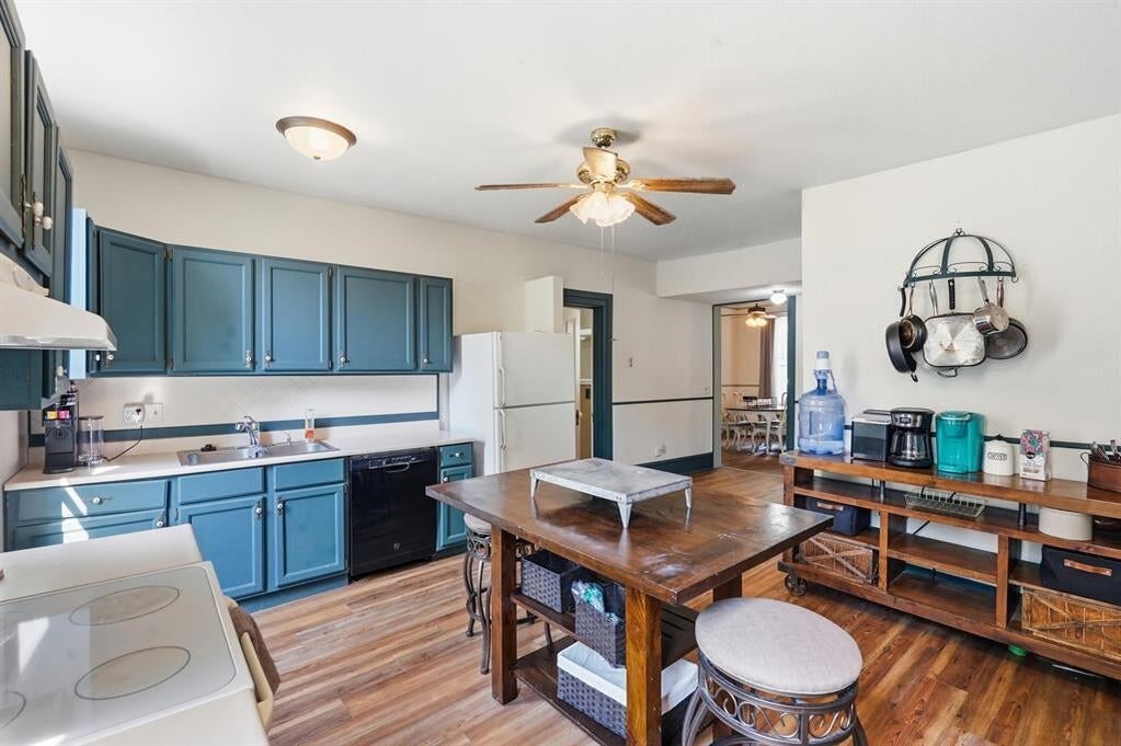 Kitchen with teal-blue cabinets, wood-look floors, and a wooden dining table with stools.