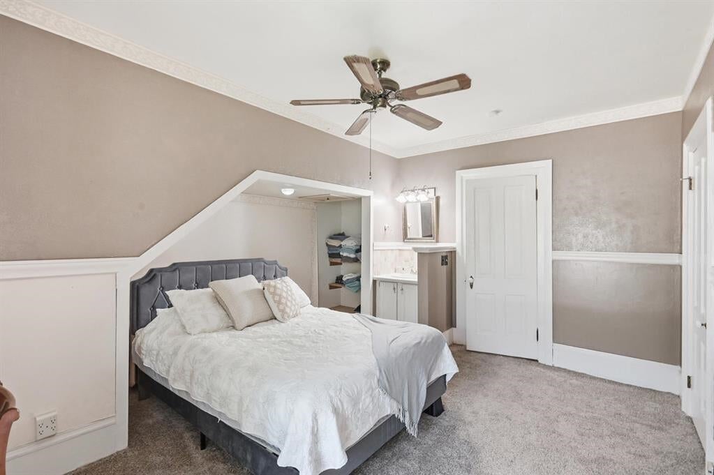 Bedroom with a gray upholstered bed, white bedding, and a ceiling fan.