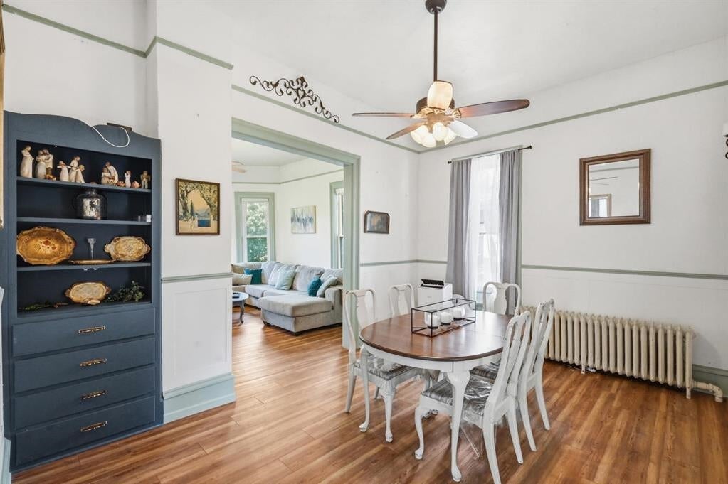 Dining room with a round table, dark blue built-in hutch, hardwood floors, and an adjoining sitting room.