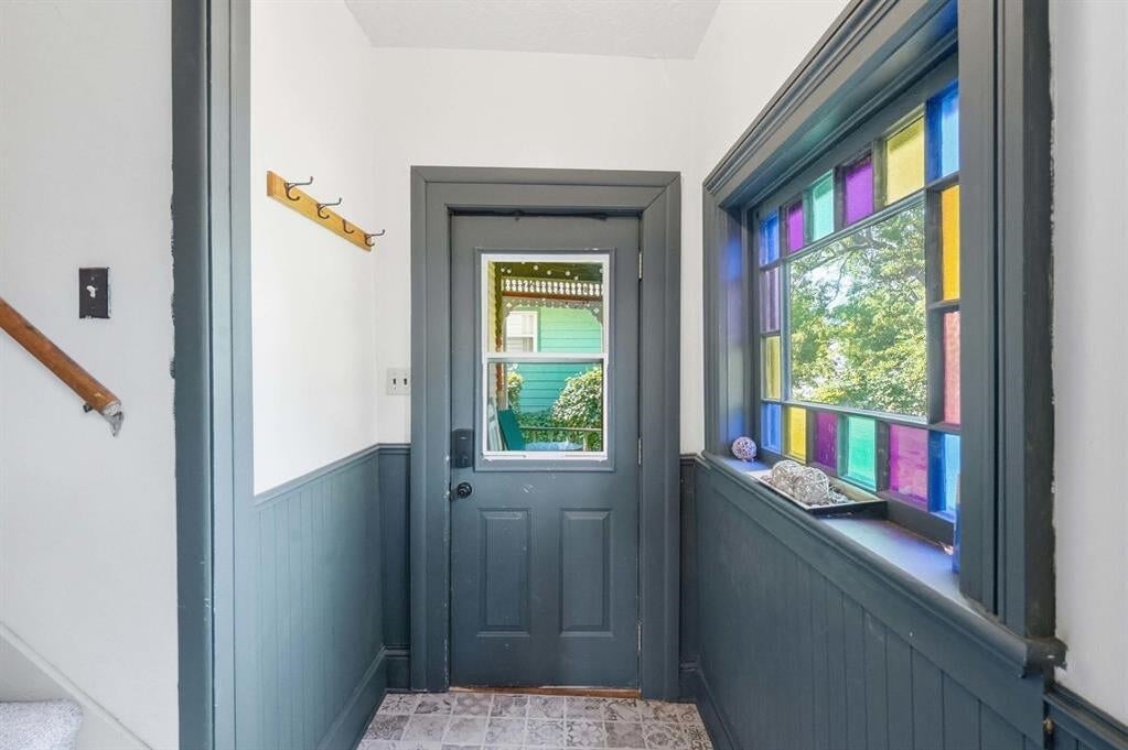 Entryway with a dark gray door, colorful stained-glass window, and patterned tile floor.