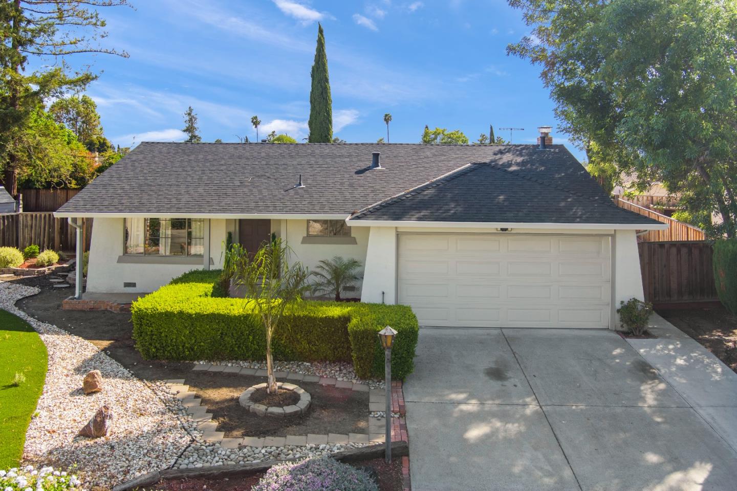 Single-story white house with a dark shingle roof, double garage, and landscaped front yard.