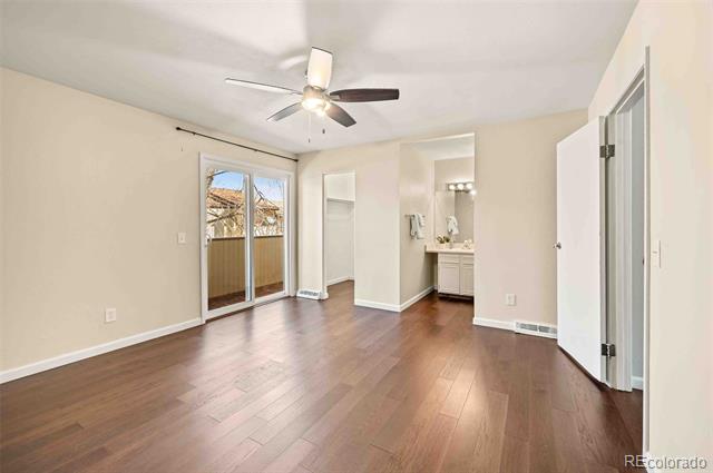 Vacant bedroom with a ceiling fan, sliding glass doors, and an adjacent vanity.