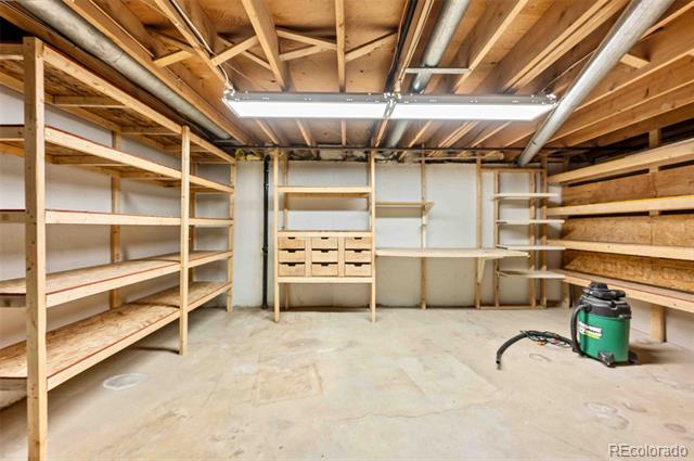 Unfinished basement storage room with extensive wooden shelving and exposed ceiling joists.