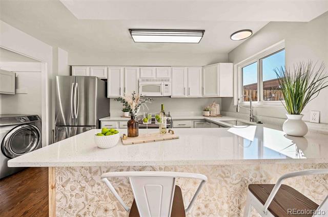 Bright kitchen with white cabinets, stainless appliances, a quartz peninsula, and a window overlooking the exterior.