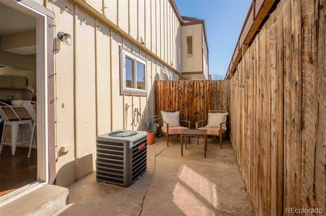 Fenced concrete patio with two chairs, a small table, and an outdoor air-conditioning unit.