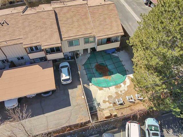 Aerial view of attached townhomes and a shared turquoise pool beside covered parking.