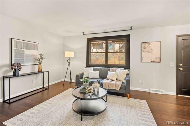 Staged living room with a gray sofa, dark-framed window, round coffee table, and pale rug.
