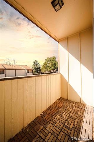 Covered balcony with patterned tile flooring and a view of trees and neighboring buildings.