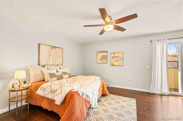 Furnished bedroom with orange bedding, a patterned rug, and a ceiling fan with light.