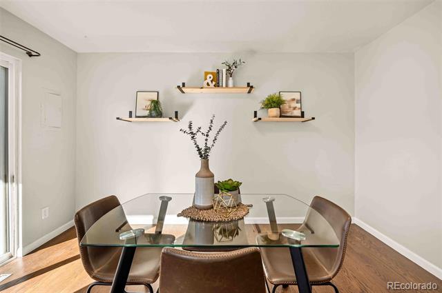 Dining room with a glass-top table, brown leather chairs, and floating shelves with plants and framed art.