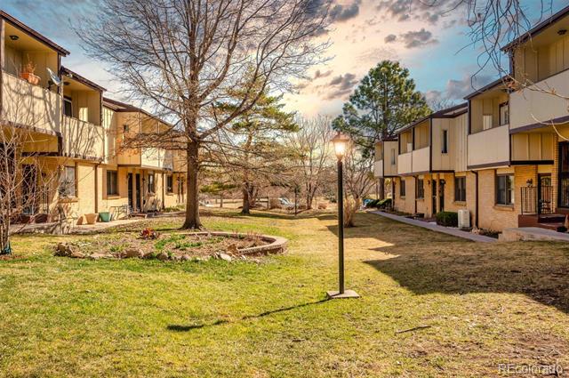 Shared residential courtyard with a lawn, large tree, and two-story buildings on either side.