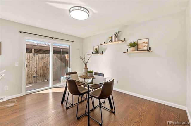 Dining room with a glass table, brown chairs, hardwood floors, and sliding doors to a fenced patio.