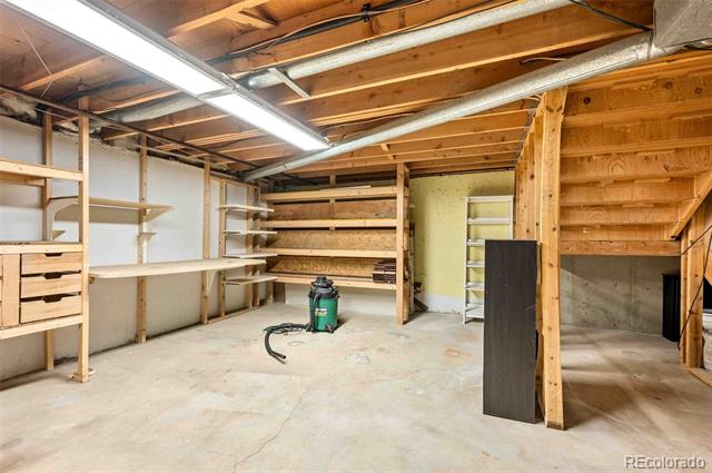 Unfinished basement with extensive wooden shelving and exposed ceiling joists.