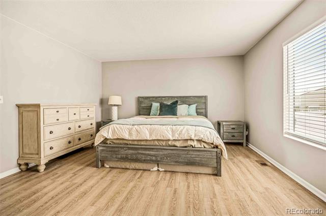 Bedroom with a gray wood bed, teal accent pillows, matching nightstand, and light wood flooring.