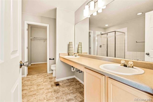 Bathroom with a long peach-toned vanity, large mirror, and glass-enclosed shower.