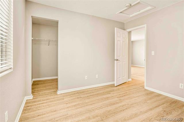 Vacant bedroom with light wood floors, an open closet, and a doorway to the hall.