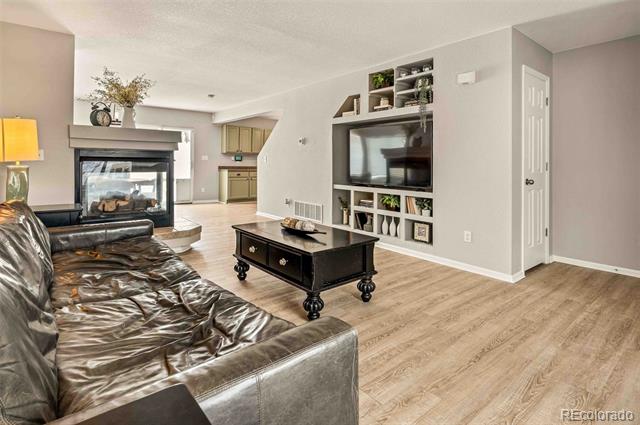 Living room with leather seating, built-in TV shelving, a fireplace, and light wood flooring.