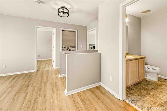 Empty landing with light wood flooring, a half-height partition, and an adjoining bathroom.