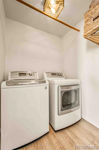 Laundry room with a top-loading washer, front-loading dryer, and wood-look flooring.