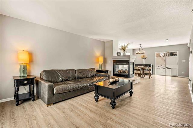 Open-plan living room with a brown leather sofa, fireplace, and light wood floors.