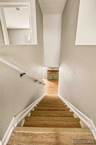 Wooden staircase with white railings descending to a landing with cabinetry.