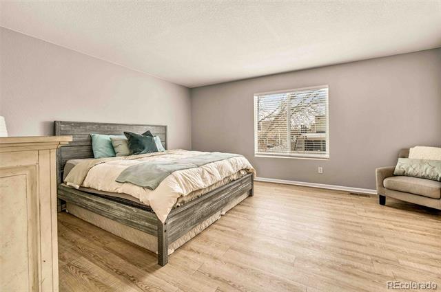 Furnished bedroom with a gray wood bed, neutral bedding, and light wood flooring.