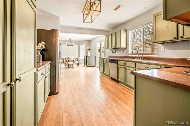 Kitchen with sage-green cabinets, wood countertops, and an adjoining dining area.