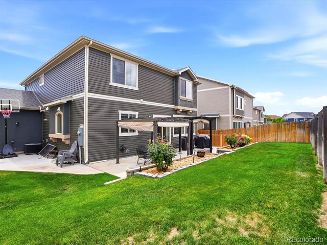 Two-story gray home with a covered patio and fenced lawn.