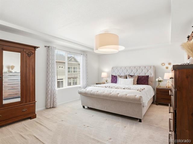 Furnished bedroom with a tufted bed, dark wood dressers, and a bright window.