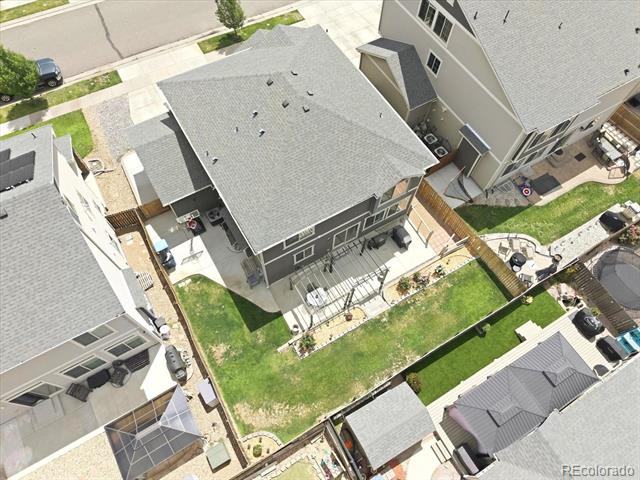 Aerial view of a gray two-story home with a fenced backyard and raised deck.
